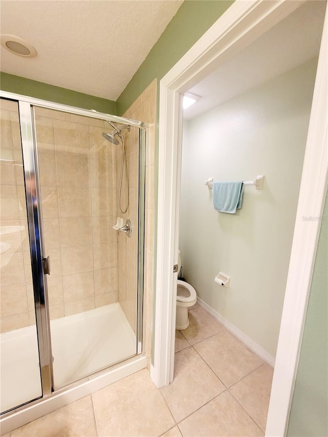 bathroom featuring toilet, tile patterned floors, and a shower with door