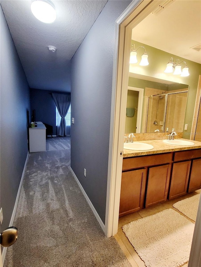 hallway with dark colored carpet, a textured ceiling, and sink