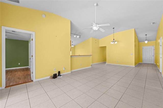 empty room featuring ceiling fan, track lighting, lofted ceiling, and light tile patterned flooring