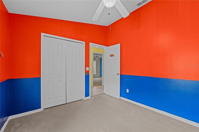 unfurnished bedroom with ceiling fan, a closet, vaulted ceiling, and light carpet