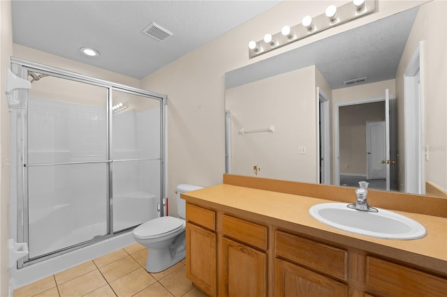 bathroom featuring tile patterned floors, a shower with shower door, a textured ceiling, vanity, and toilet