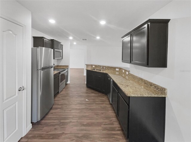 kitchen featuring appliances with stainless steel finishes, sink, dark wood-type flooring, and light stone countertops