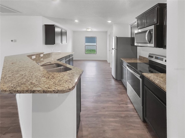 kitchen with sink, dark wood-type flooring, light stone counters, and stainless steel appliances