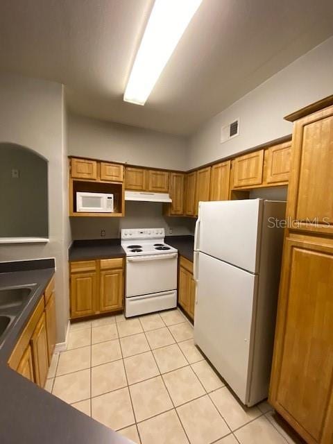 kitchen featuring sink, light tile patterned flooring, and white appliances