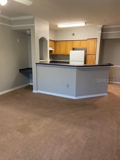 kitchen featuring light carpet, kitchen peninsula, crown molding, and white fridge