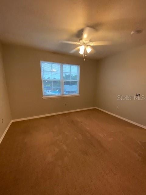 carpeted spare room featuring ceiling fan