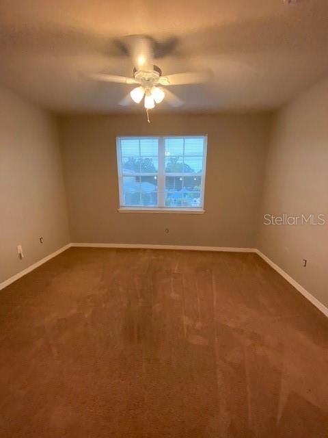 carpeted spare room featuring ceiling fan