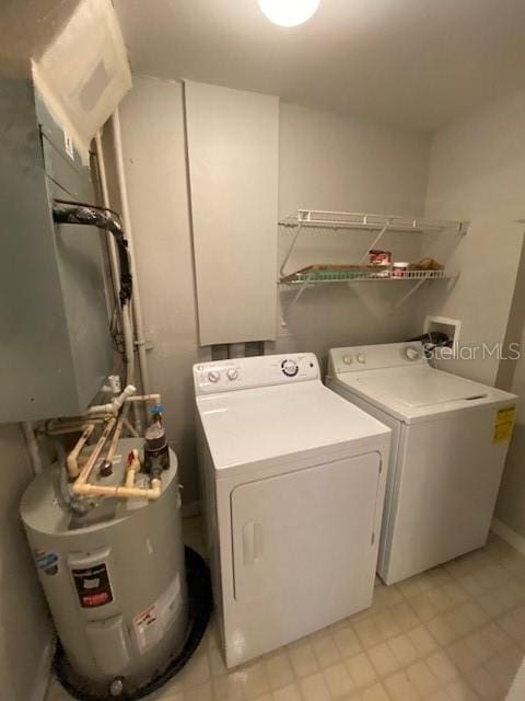 clothes washing area with light tile patterned floors, washing machine and clothes dryer, and water heater