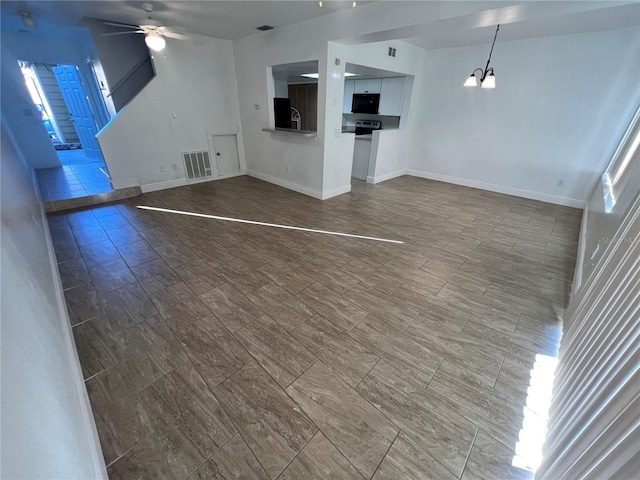 unfurnished living room featuring tile patterned floors, sink, and ceiling fan with notable chandelier