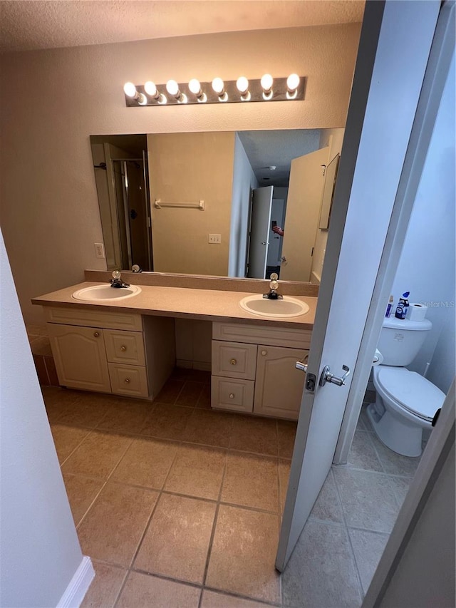 bathroom with tile patterned flooring, toilet, a textured ceiling, and vanity