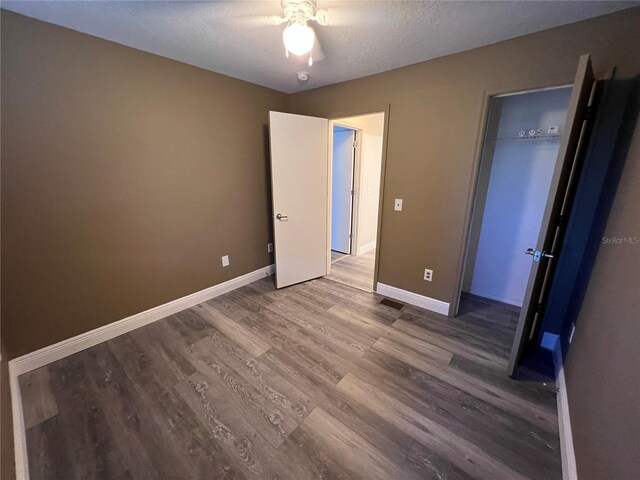 unfurnished bedroom with hardwood / wood-style flooring, a closet, a textured ceiling, and ceiling fan