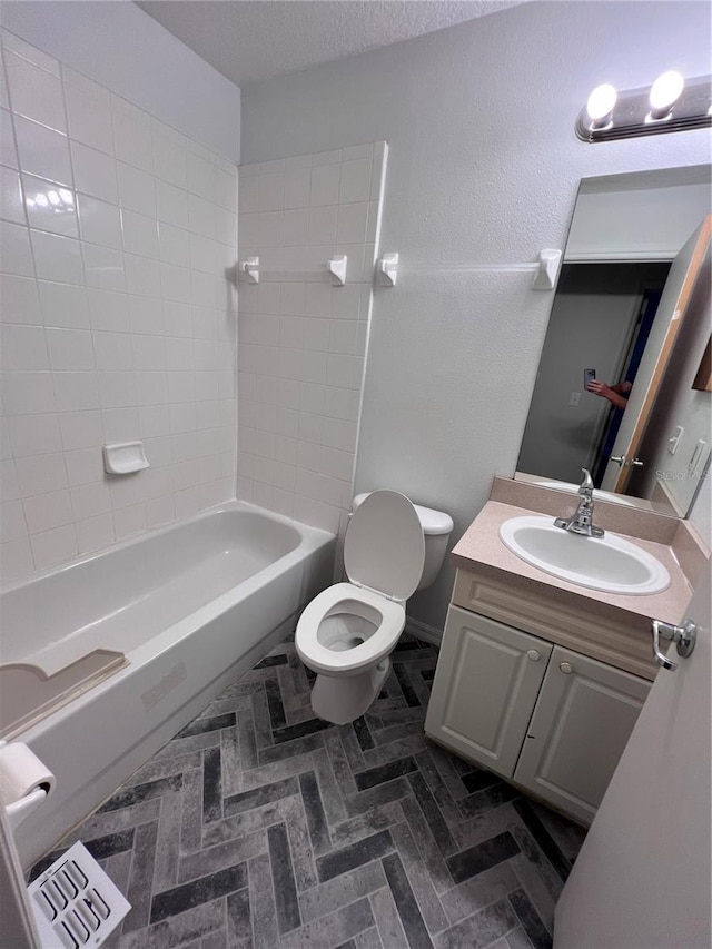 full bathroom with tiled shower / bath, vanity, and toilet