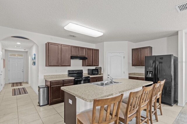 kitchen with arched walkways, a sink, visible vents, under cabinet range hood, and black appliances