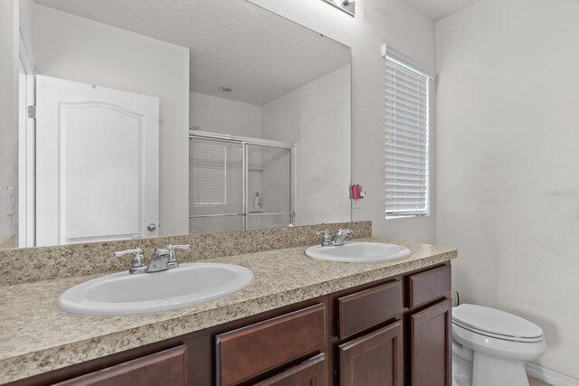 full bathroom featuring toilet, a sink, double vanity, and a stall shower