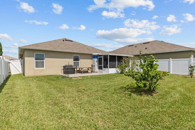 rear view of house with a fenced backyard, a yard, a sunroom, a patio, and stucco siding