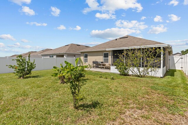 rear view of property with a lawn, a shingled roof, a fenced backyard, a patio, and a sunroom