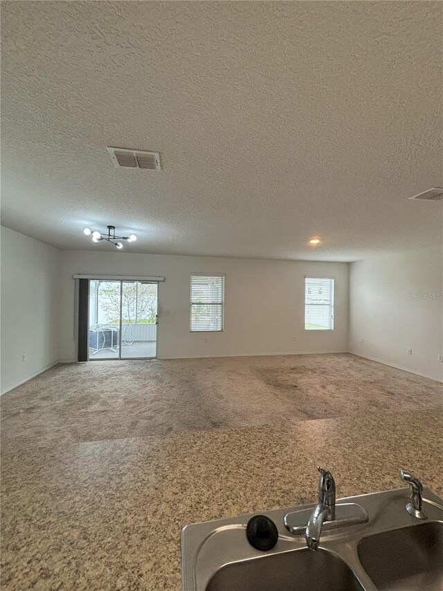 interior space with a textured ceiling, plenty of natural light, visible vents, and a sink