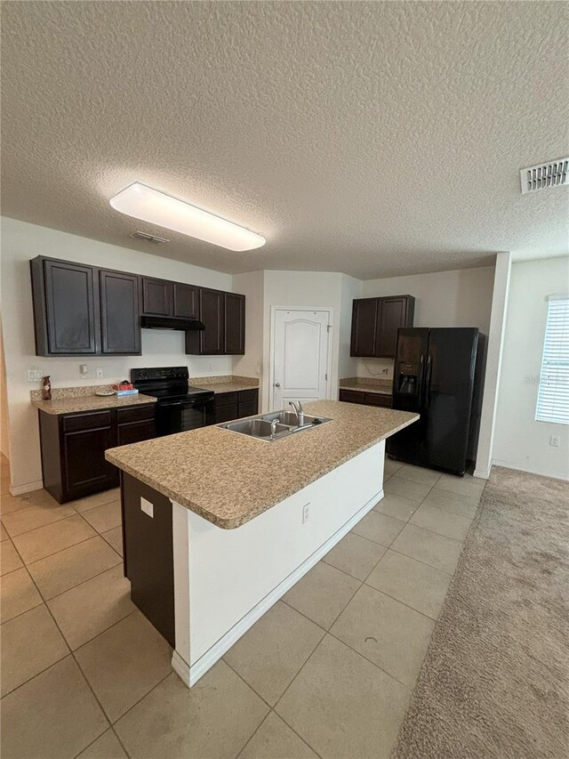 kitchen with under cabinet range hood, visible vents, light tile patterned floors, a sink, and black appliances