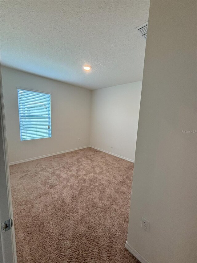 spare room featuring carpet floors, a textured ceiling, and baseboards