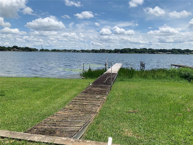 view of dock featuring a lawn and a water view