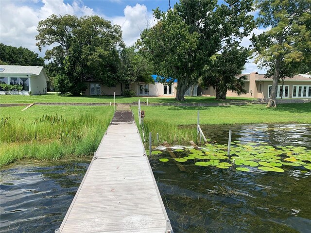 view of dock featuring a lawn and a water view