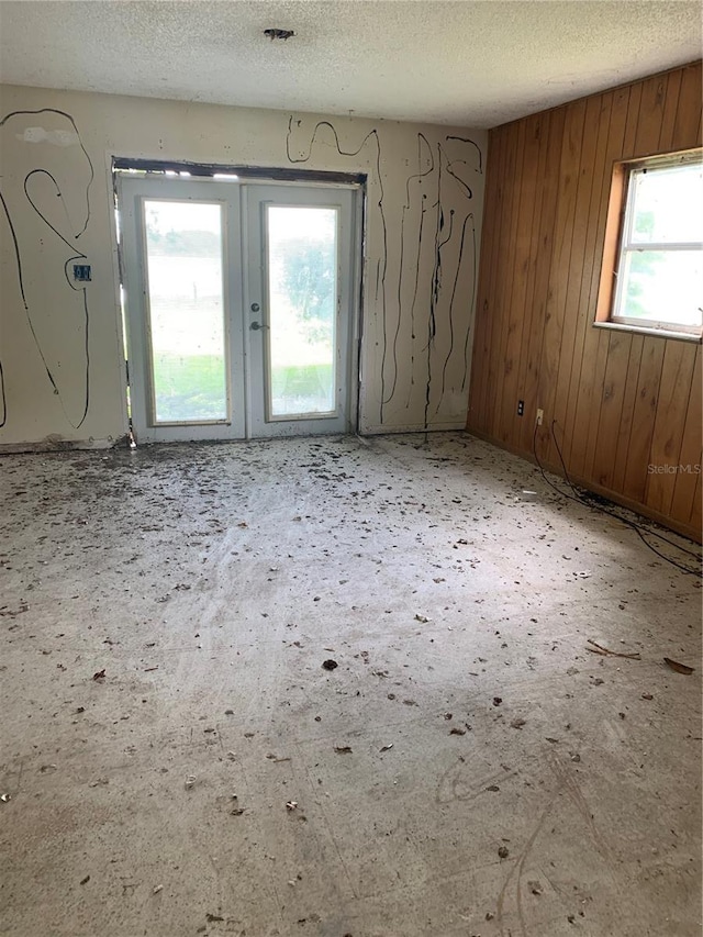 empty room with wood walls and a textured ceiling