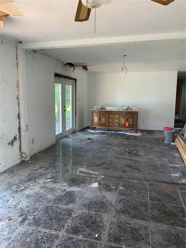 spare room with ceiling fan, a textured ceiling, and dark tile patterned floors