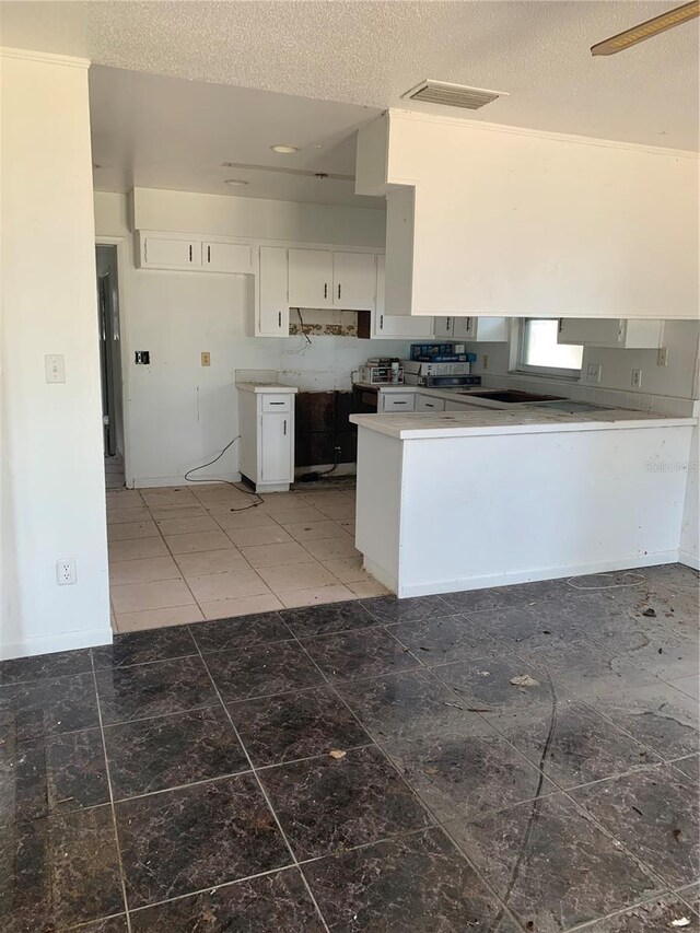 kitchen featuring a textured ceiling, dark tile patterned floors, and white cabinetry