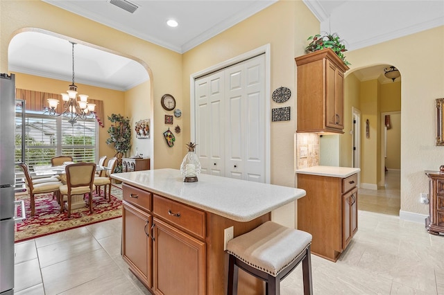 kitchen with a kitchen island, an inviting chandelier, crown molding, hanging light fixtures, and light tile patterned flooring