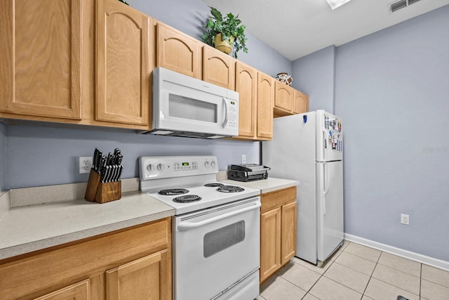 kitchen with light tile patterned flooring, white appliances, and light brown cabinetry