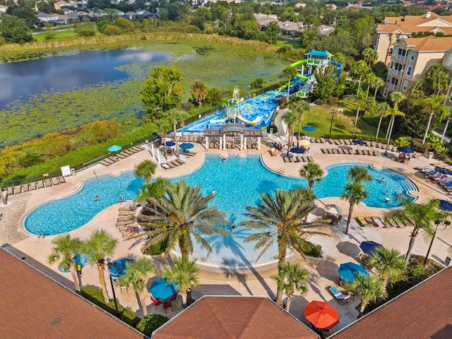 view of pool with a water slide, a water view, and a patio