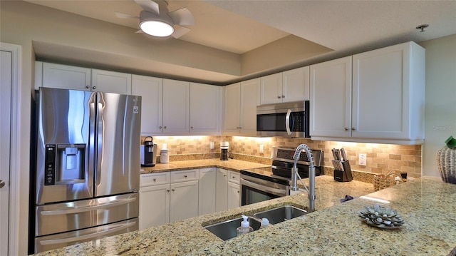 kitchen with appliances with stainless steel finishes, light stone counters, backsplash, and white cabinets