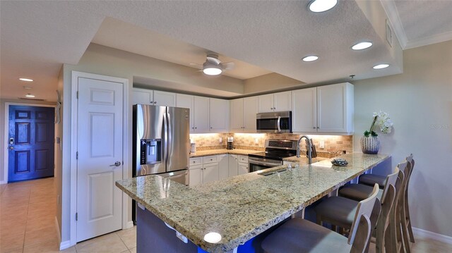 5300 S Atlantic Ave Unit 16-602, New Smyrna Beach, FL 32169 - kitchen featuring appliances with stainless steel finishes, light stone counters, a peninsula, a kitchen bar, and tasteful backsplash