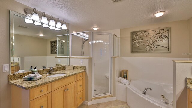 5300 S Atlantic Ave Unit 16-602, New Smyrna Beach, FL 32169 - bathroom with vanity, a textured ceiling, a stall shower, a jetted tub, and tile patterned flooring
