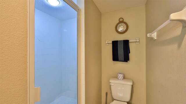 bathroom featuring a shower with shower door and toilet