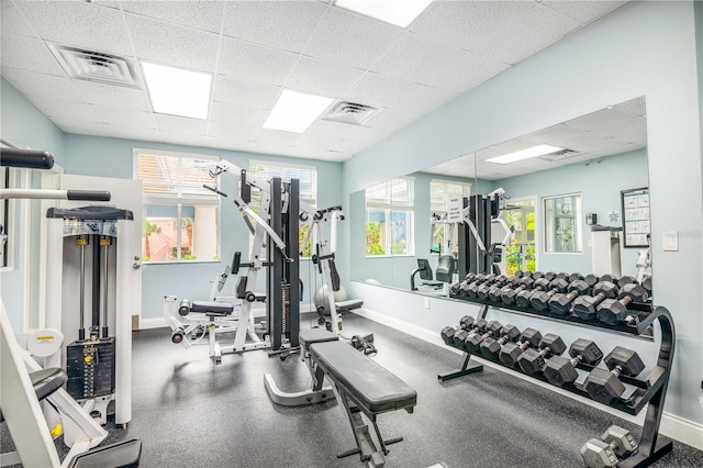 gym featuring a paneled ceiling and a healthy amount of sunlight