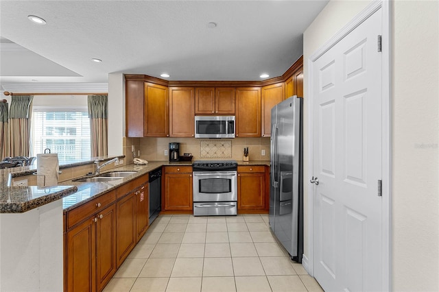 kitchen with dark stone countertops, light tile patterned floors, stainless steel appliances, and kitchen peninsula