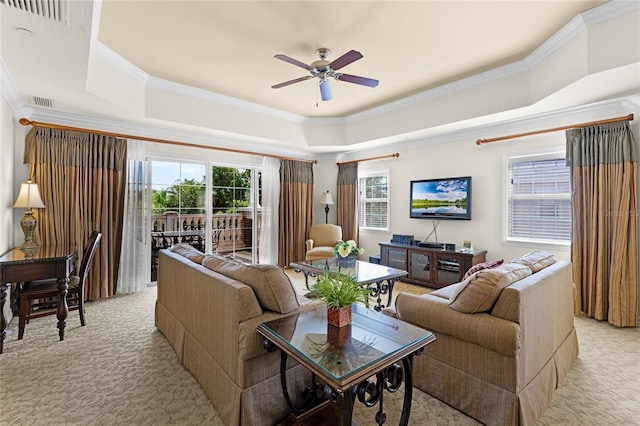 living room with light colored carpet, ceiling fan, ornamental molding, and a tray ceiling