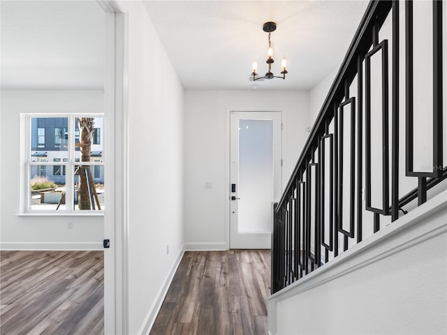 entrance foyer featuring an inviting chandelier, baseboards, stairway, and wood finished floors