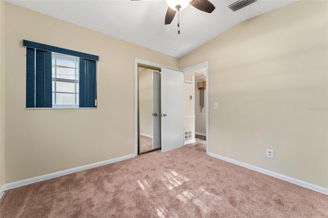 empty room with ceiling fan, lofted ceiling, and light colored carpet