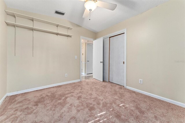 unfurnished bedroom with ceiling fan, light colored carpet, a closet, and lofted ceiling