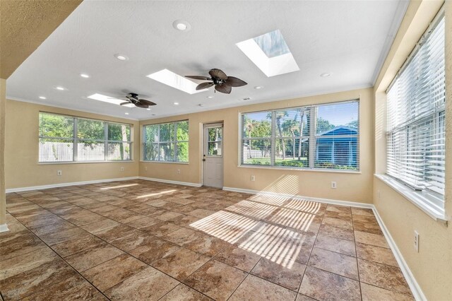 tiled empty room featuring ceiling fan, a skylight, and ornamental molding