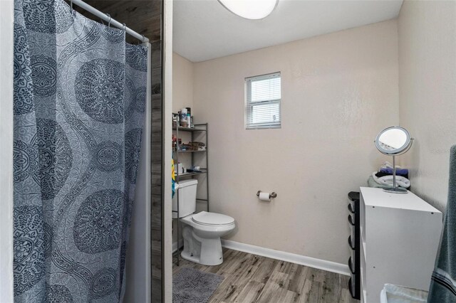 bathroom with hardwood / wood-style floors, toilet, and a shower with curtain