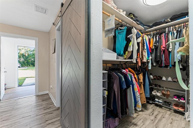 spacious closet featuring light hardwood / wood-style floors and a barn door