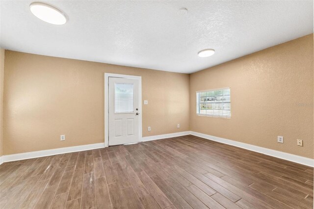 unfurnished room with hardwood / wood-style flooring and a textured ceiling