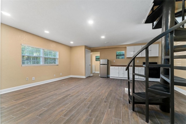 basement featuring hardwood / wood-style flooring and stainless steel refrigerator