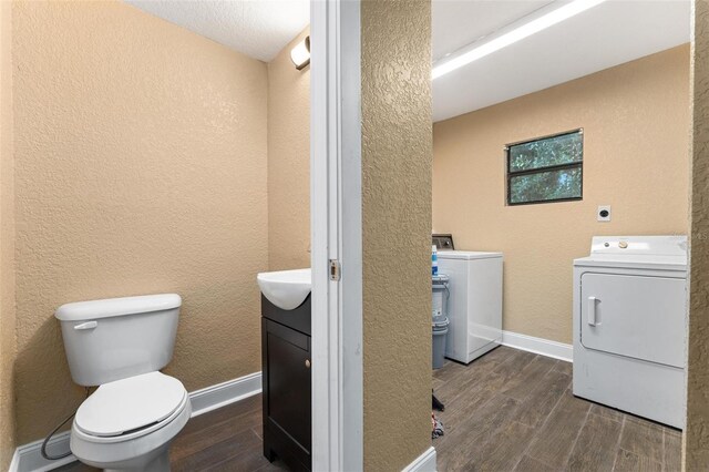 bathroom featuring washer and dryer, wood-type flooring, toilet, and vanity