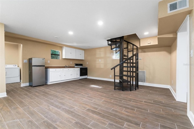 interior space with washer / clothes dryer, hardwood / wood-style flooring, and stainless steel refrigerator