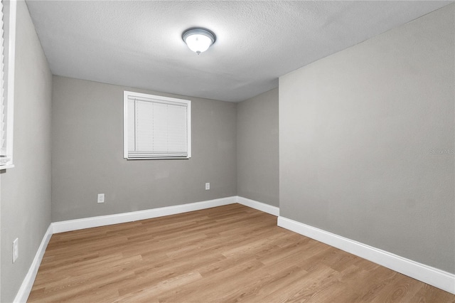 empty room with a textured ceiling and light wood-type flooring