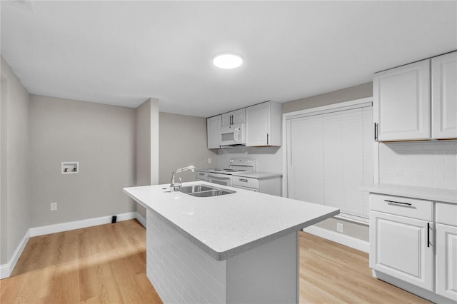 kitchen with white cabinets, a kitchen island with sink, light hardwood / wood-style floors, sink, and white appliances